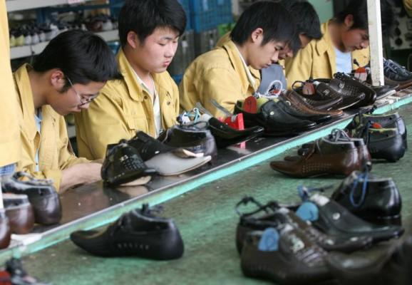 Fabriksarbetare kvalitetskontrollerar skor vid en produktionslinje på skofabriken Kangnai i den kinesiska staden Wenzhou. (Foto: Mark Ralston/AFP/Getty Images)
