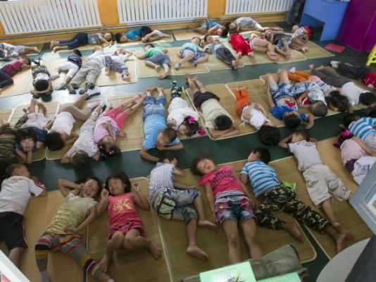 Migrantarbetares barn under middagsvilan den 26 juni 2012 på en olaglig migrantskola i Peking. Skolan har fått order om att stänga, vilket resulterar i att barnen måste återvända till sina hemprovinser. (Foto: STR/AFP/Getty Images)