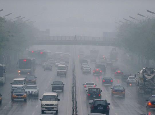 För miljontals människor är det här den miljö man lever i. Nu har forskarna upptäckt att risken att drabbas av hjärtsymtom ökar redan efter två timmars exponering i smutsig stadsluft. I Kina finns 16 av världens 20 mest förorenade städer. På bilden  promenerar en fotgängare över en smogfylld och hårt trafikerad väg i Peking den 23 april 2009. (Foto: Fredric J.Brown/AFP)
