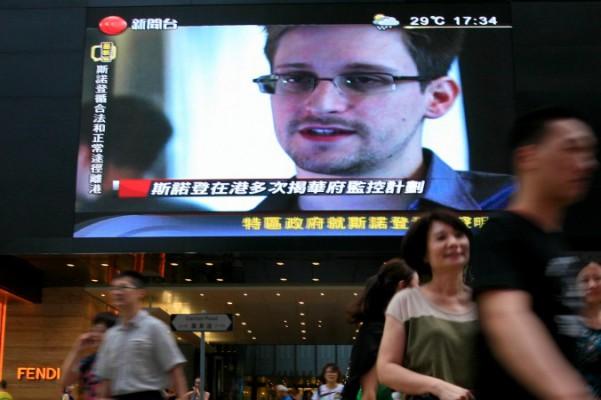 På en TV-skärm visas nyheter om Edward Snowden, en före detta CIA-anställd som läckt topphemliga dokument om amerikanska övervakningsprogram. Platsen är ett köpcentrum i Hongkong den 23 juni 2013. Snowden var en het potatis i Hongkong som det kinesiska kommunistpartiet nu har avhänt sig, till Rysslands glädje. (Foto: AP Photo/Vincent Yu)