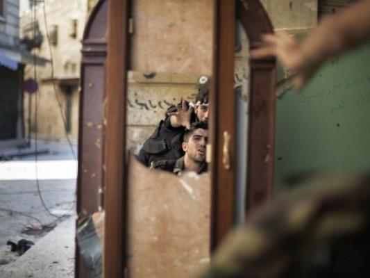Soldater från den Fria syriska armén syns i en spegel som används för att se en postering från Syriska armén femtio meter bort i den gamla staden Aleppo den 16 september. (Foto: Marco Longari/AFP/GettyImages)
