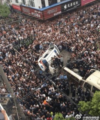 Den arga folkmassan välter en ambulans i staden Wenzhou i Zhejiangprovinsen den 19 april. Över 1 000 personer angrep fem ordningspoliser, chengguan på kinesiska, efter att de gett sig på en person. (Foto från Weibo)