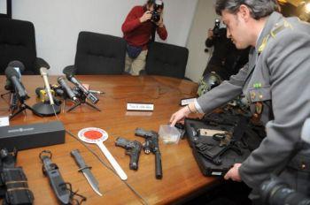 En medlem av Italiens ekobrottspolis visar upp pistoler, kulor och andra vapen som använts av de misstänkta. Bilden togs vid italienska ekobrottspolisens presskonferens den 3 mars i Milano.
