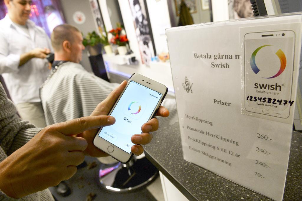 En person betalar med Swish via mobiltelefonen på en frisörsalong. (Foto: Fredrik Sandberg/TT)
