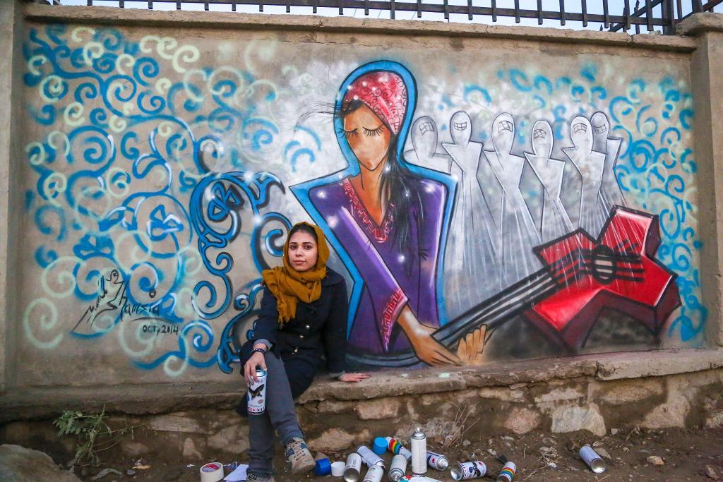 Shamsia Hassani framför en av sina graffitiverk i Kabul. I sina målningar vill hon ge en bild av kvinnorna under burkan. (Foto: Shamsia Hassani/TT)