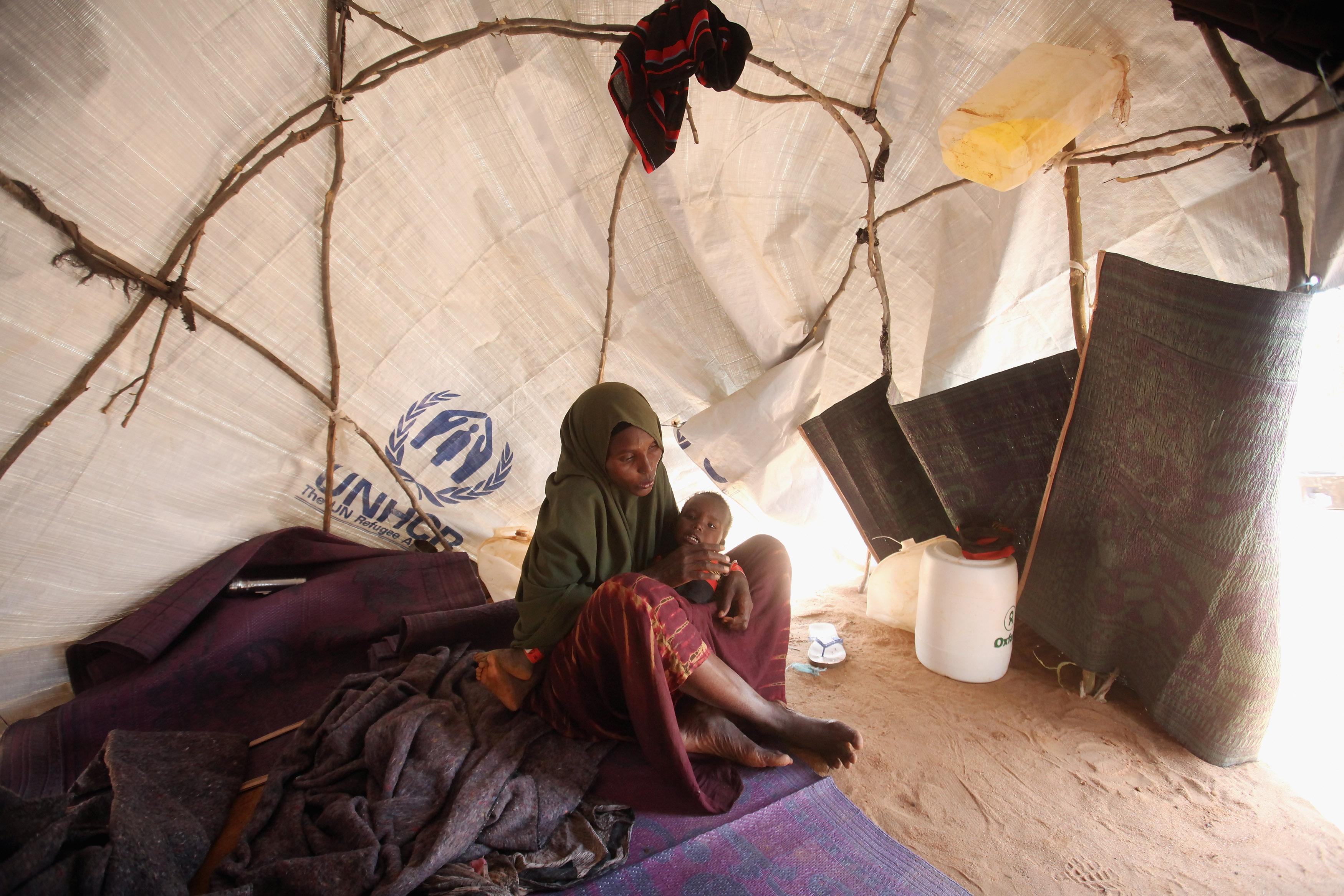 I ett flyktingläger nära gränsen till Somalia, i Kenya, sitter en mor med sitt undernärda barn. FN:s mål är att utrota fattigdom och hunger.  (Foto: Oli Scarff/Getty Images) 