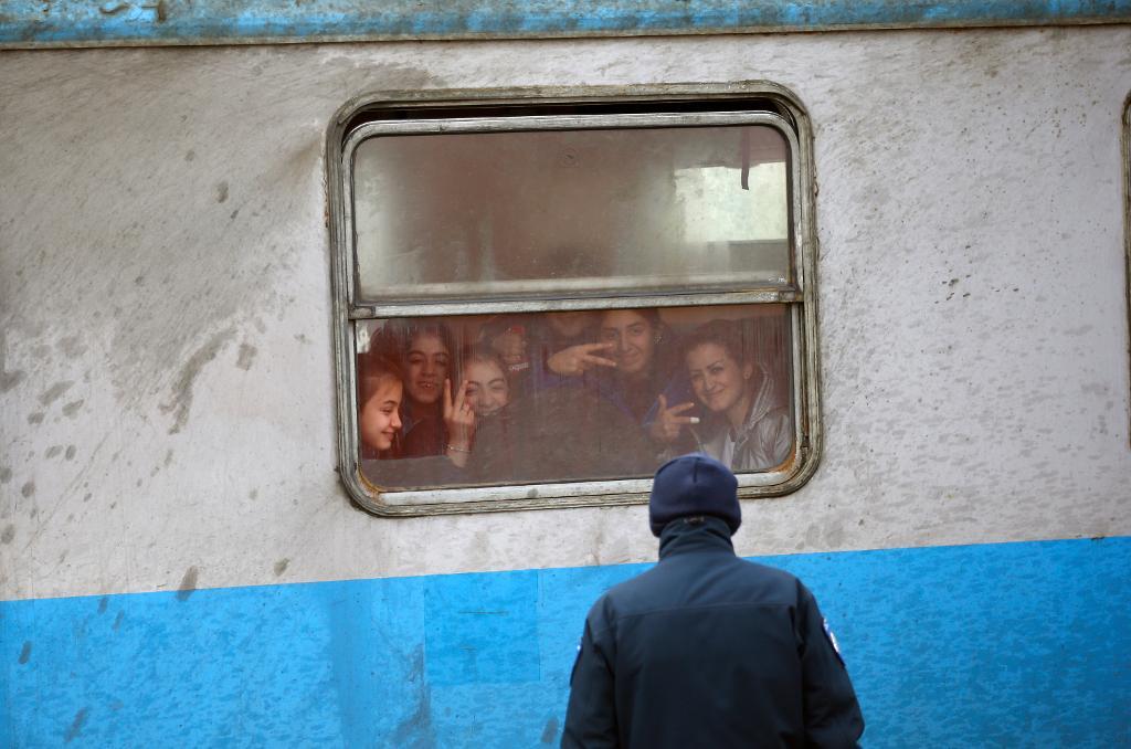En polis betraktar migranter i ett tåg som ska avgå till Kroatien från den serbiska staden Sid. (Foto: Darko Vojinovic/AP/TT)