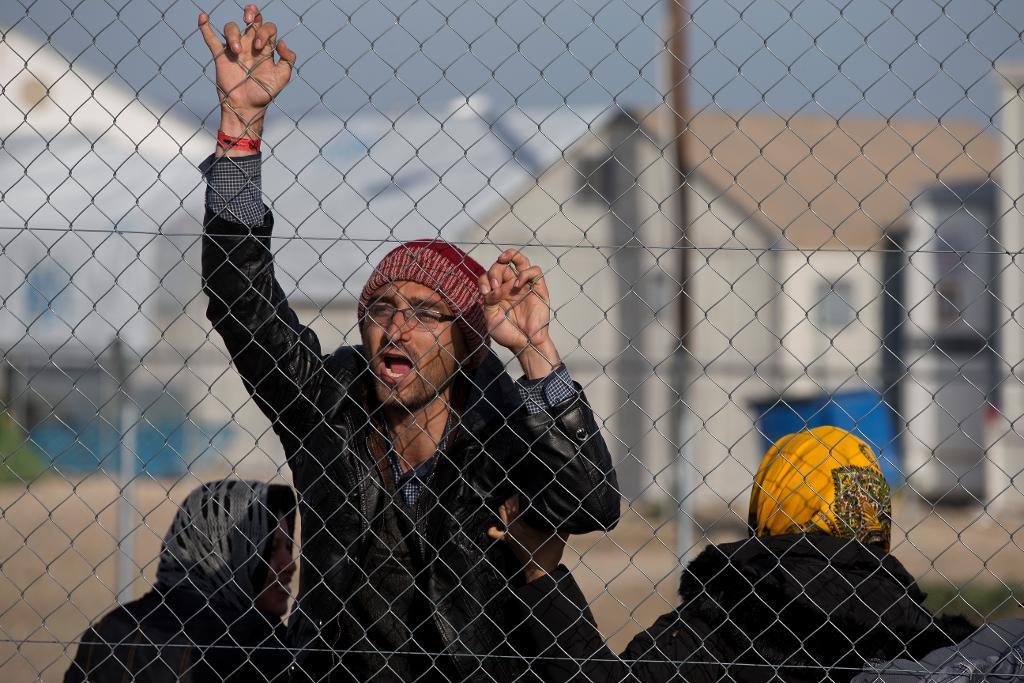 "Hjälp oss Merkel!" ropar en afghansk migrant vid Greklands norra gräns, när polisen tidigt i tisdags morse befallde främst afghanska migranter att gå ombord på bussar för att köras till ett nybyggt flyktingläger utanför Aten. EU vill pressa Grekland att fullfölja sitt arbete med flyktingar och migranter och erbjuda tillfälliga boendemöjligheter. (Foto: Petros Giannakouris / AP/ TT-arkivbild)