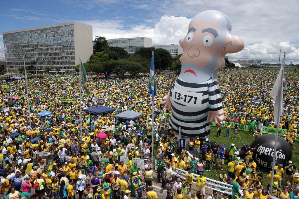 En fångklädd, uppblåsbar docka föreställande expresident Lula tornar upp sig över demonstranterna i Brasília. (Foto: Eraldo Peres /AP/TT)