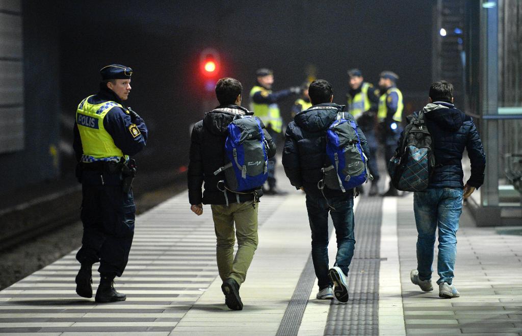 Polis eskorterar asylsökande från ett Öresundståg som stannat vid Hyllie station utanför Malmö efter genomförd gränskontroll. (Foto: Johan Nilsson /TT-arkivbild)