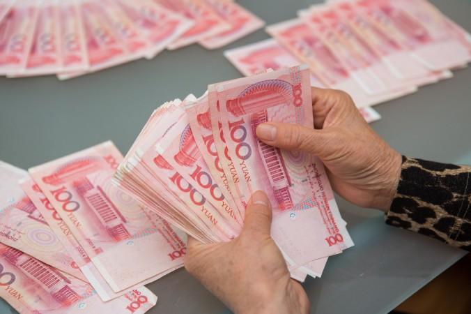 100-yuansedlar som räknas. (Foto: Benjamin Chasteen /Epoch Times)