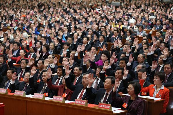Delegater i Kinas variant på en lagstiftande församling, Nationella folkkongressen, räcker upp handen för att rösta ”ja” under en samling i mars 2012. (Foto: Nandu)