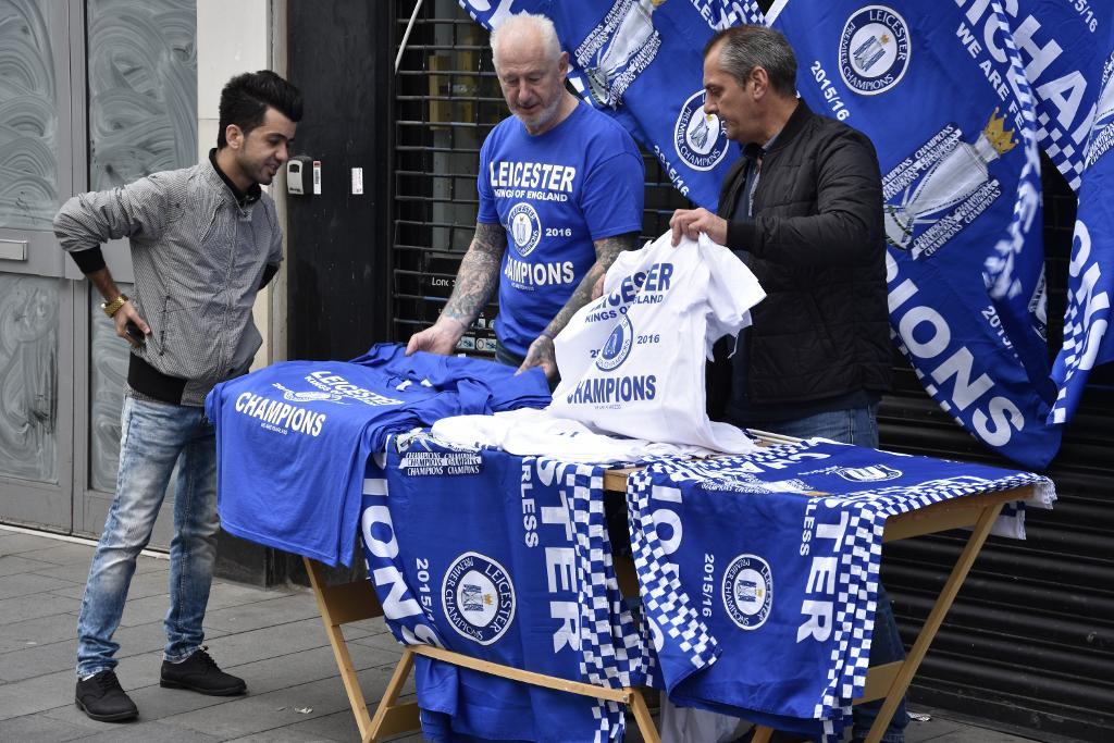Leicester-supportrarna Sym (i mitten) och Mark (till höger) säljer mästartröjor och mästarflaggor för glatta livet. Båda är övertygade om att Leicester Citys första ligatitel snart är i hamn. (Foto: Viktor Nummelin/TT)