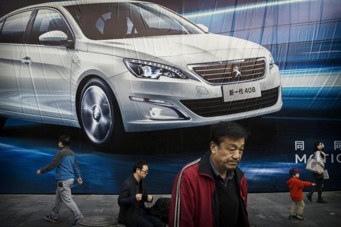 De kinesiska ledarnas ekonomiska reformplan står inför flera strukturella hinder. På bilden ses människor i Peking framför en enorm annons för en utländsk biltillverkare. (Foto: Kevin Frayer/Getty Images)