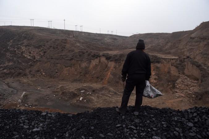 En kvinna står på en kolhög nära en kolgruva i Datong, i Shanxi-provinsen. Kol har visat sig vara en sektor som är svår att reformera. (Foto: Greg Baker/AFP/Getty Images)