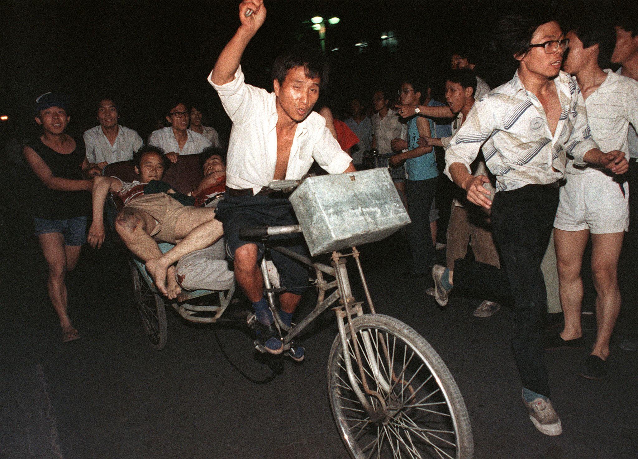 Skadade förs bort efter arméns attack mot demokratiprotesterna på Himmelska fridens torg den 4 juni 1989. Som alltid kring årsdagen hamnar den kinesiska regimens ihärdiga vägran att erkänna och ta i de här händelserna i fokus. (Foto: Manuel Ceneta/AFP/Getty Images)