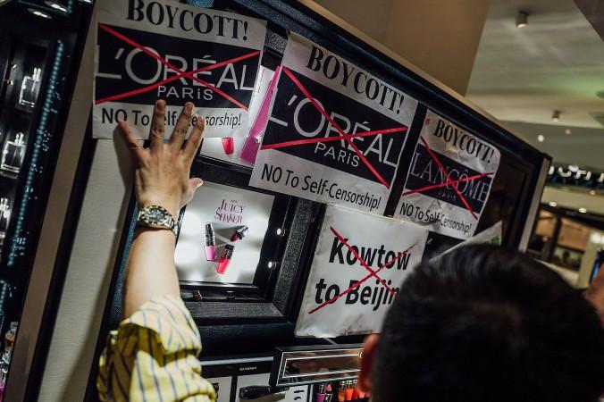 
Demonstranter sätter upp affischer och ropar slagord mot det franska kosmetikamärket Lancôme utanför dess butik i Hongkong den 8 juni i år. (Foto: Anthony Kwan/Getty Images)