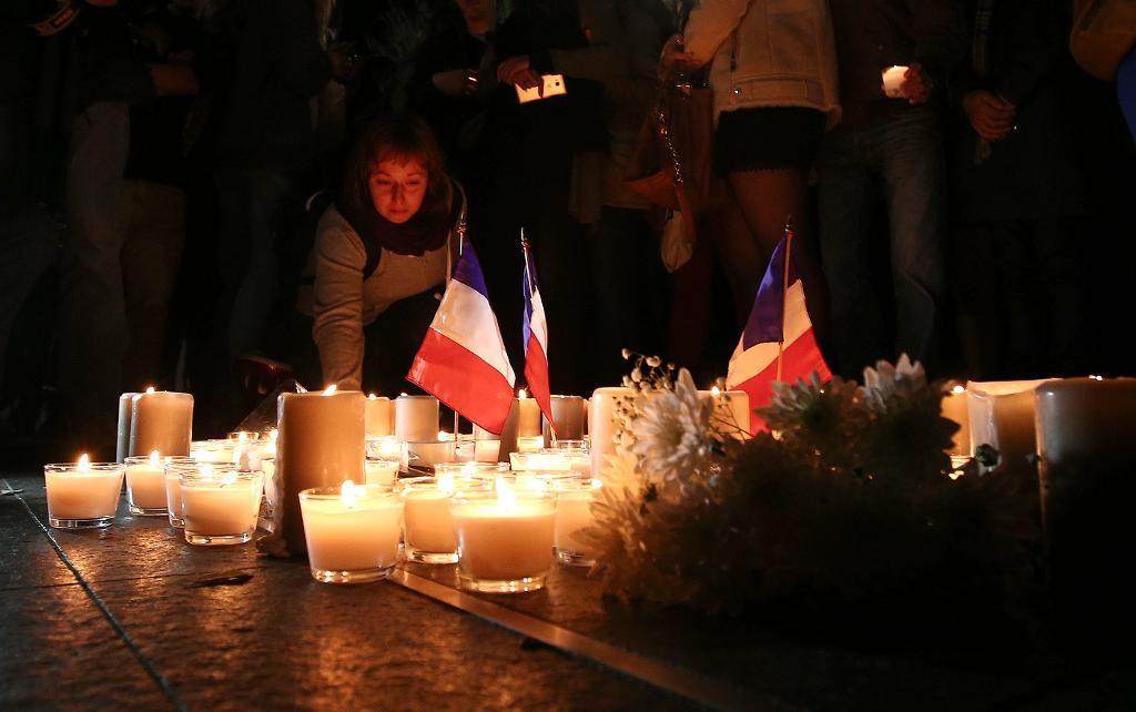 En kvinna tänder ljus för att hedra offren för nationaldagskvällens attentat. (Foto: Rob Griffith/AP/TT)