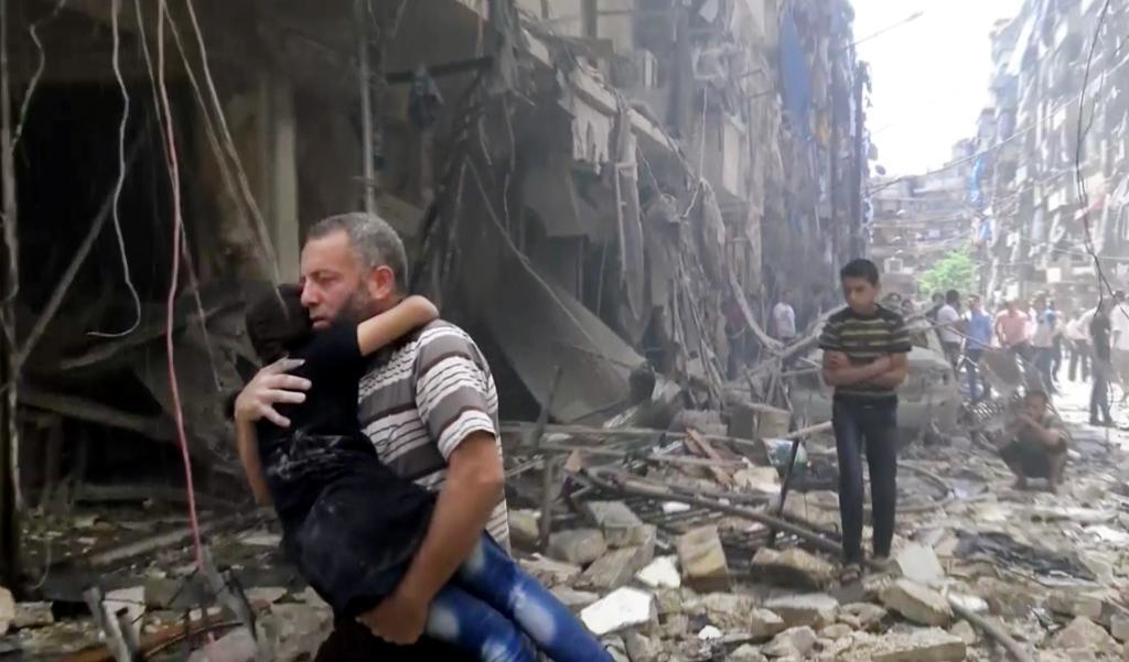 
En man bär sitt barn efter att en luftattack drabbat Aleppo i Syrien. (Foto: TT Arkivbild)