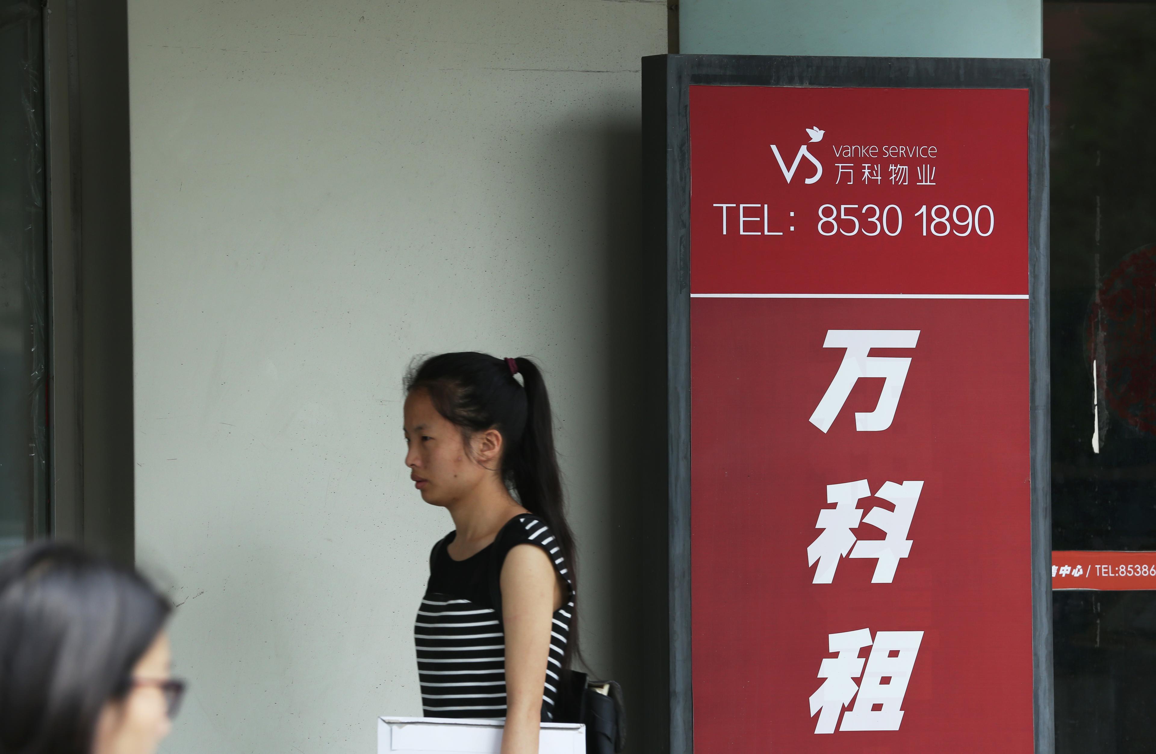 En kvinna går förbi en skylt utanför ett av fastighetsjätten Vankes servicecenter i Peking. Kampen om makten över Vanke håller på att utvecklas till ett riktigt drama, med konsekvenser för hur kommunistpartiet ska hantera den privata sektorn framöver. (Foto: STR/AFP/Getty Images)
