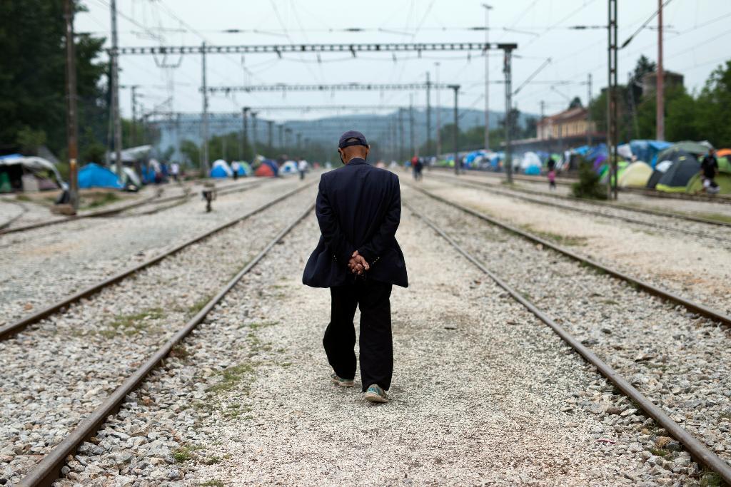 En man promenerar längs ett järnvägsspår vid ett tillfälligt flyktingläger vid Idomeni, i norra Grekland. (Foto: Petros Giannakouris /arkivbild)