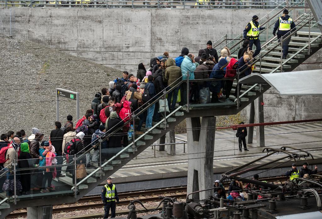Polis övervakar kön av ankommande flyktingar i snålblåsten vid Hyllie station utanför Malmö i november i fjol. (Foto: Johan Nilsson/TT)