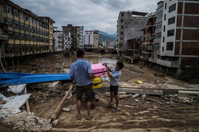 Människor lämnar den tyfondrabbade byn Bandong i Fujianprovinsen i Kina, 12 juli 2016. En student som rapporterat om en annan bild än den de statliga medierna ville ge av katastrofen har nu gripits, enligt människorättsorganisationer. (Foto: Lam Yik Fei/Getty Images)