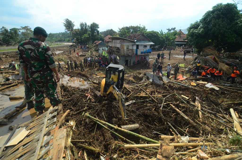 Räddningsarbetare söker efter offer i det som finns kvar av en by som träffades av översvämningen. (Foto: AP/TT)