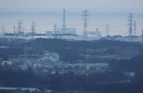 I bakgrunden syns Fukushima Daiichi kärnkraftverk, den 11 mars 2016 - fem år efter en av världshistoriens allvarligaste kärnkraftsolyckor som tillsammans med tsunamin kostade runt 18 500 liv. Nu funderar Japan på att återgå till kärnkraft.  (Foto: Jiji Press/AFP/Getty Images)