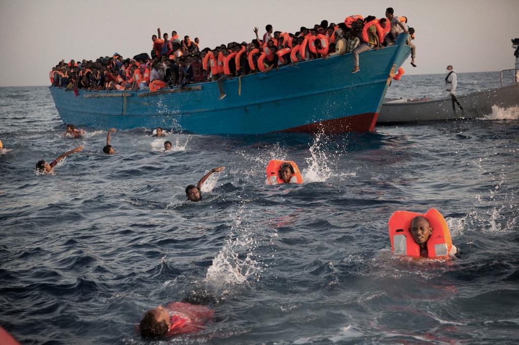 Migranter, de flesta från Eritrea, hoppar i vattnet från en överlastad träbåt för att tas om hand av medlemmar i en frivilligorganisation. Arkivbild.
(Emilio Morenatti/AP/TT)