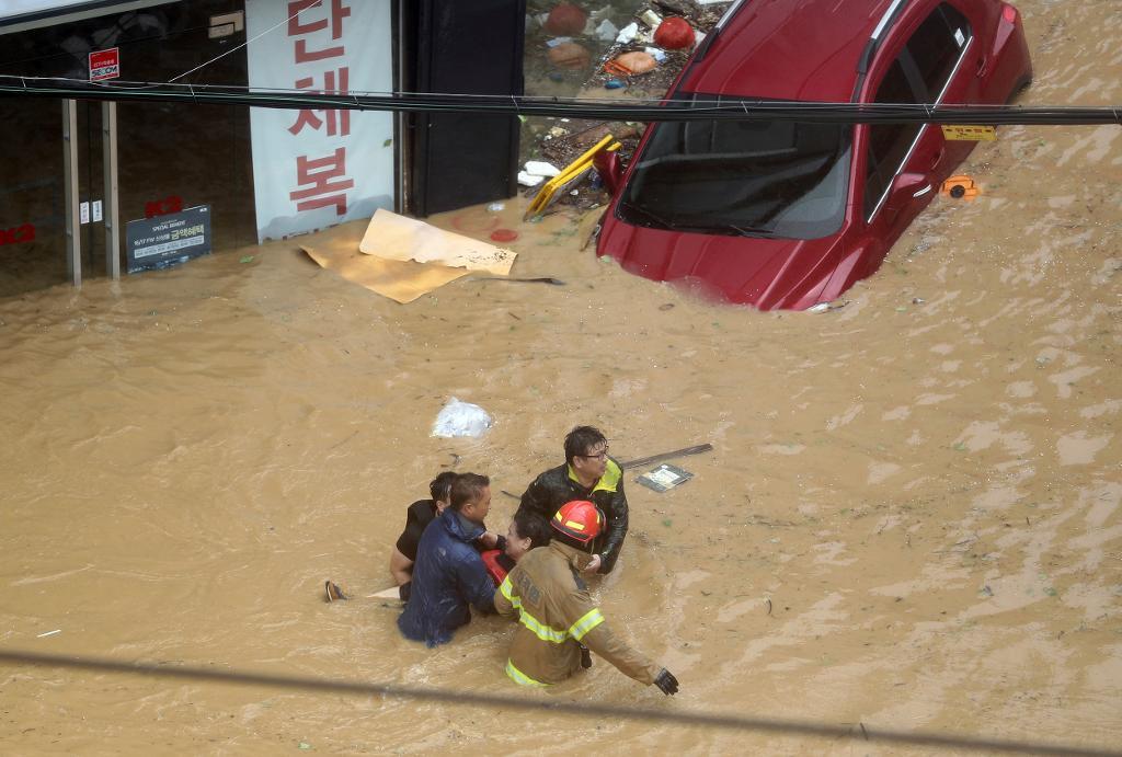Räddningsarbetare bär en boende genom en översvämmad gata i Ulsan, Sydkorea. (Foto: Lee Sang-hyun/AP/TT)