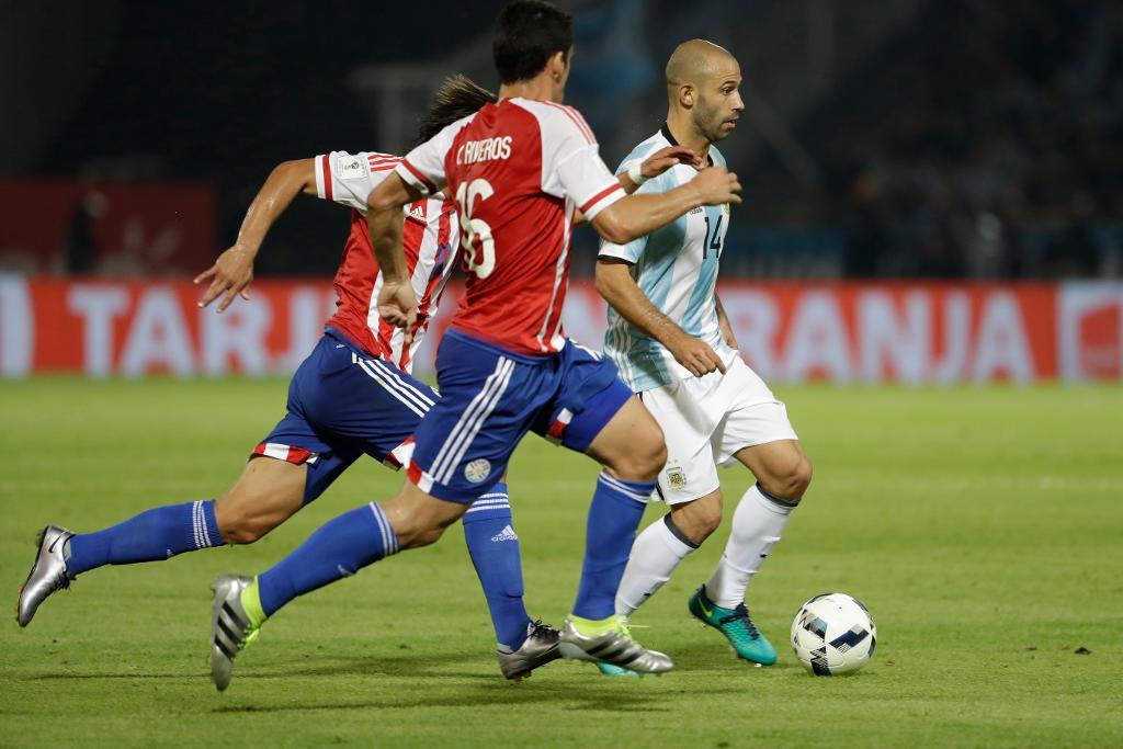 Argentinas Javier Mascherano dribblar förbi Paraguays Cristian Riveros. (Foto: Natacha Pisarenko/AP/TT)