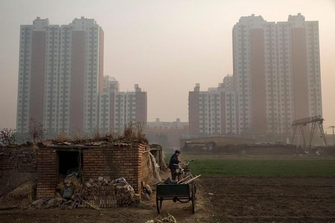 En bild från Pekings utkanter i november 2014. En äldre bonde utanför sitt hem, med ett nytt förortsområde i bakgrunden. (Foto: Kevin Frayer/Getty Images)