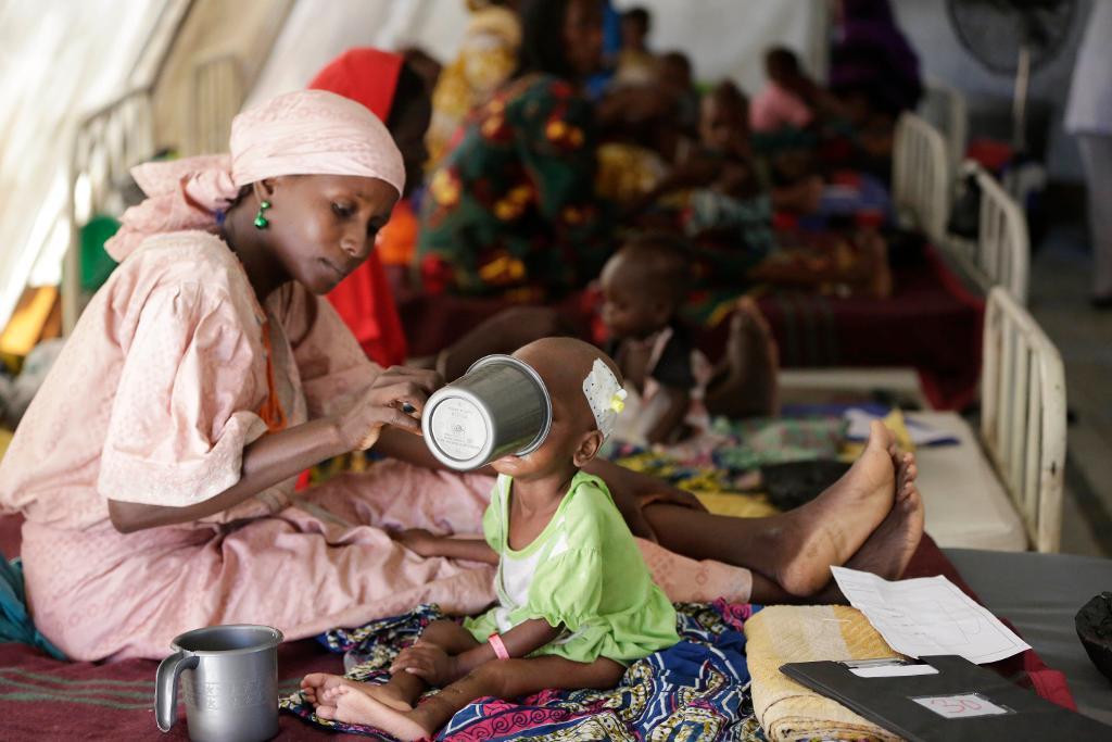 En mamma matar sitt undernärda barn på en klinik i Maiduguri i Nigeria. 75 000 nigerianska barn riskerar att dö om de inte får hjälp, larmar FN.(Foto: Sunday Alamba/AP/TT-arkivbild)
