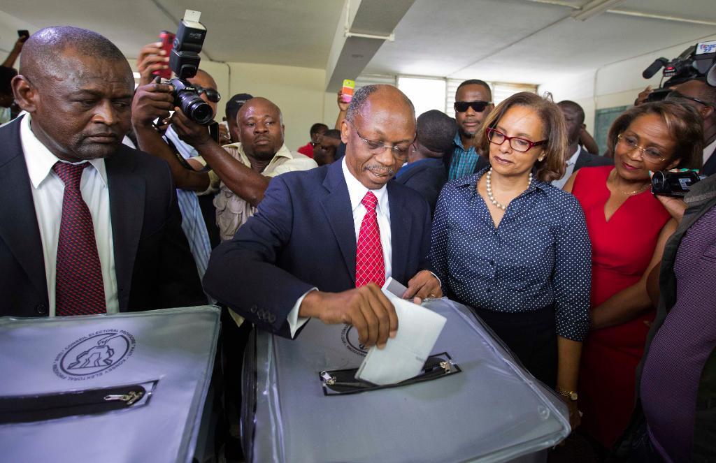 
Den förre presidenten Jean-Bertrand Aristide lägger sin röst på Maryse Narcisse, till höger i röd klänning, i presidentvalet. (Foto: Dieu Nalio Chery/AP/TT)