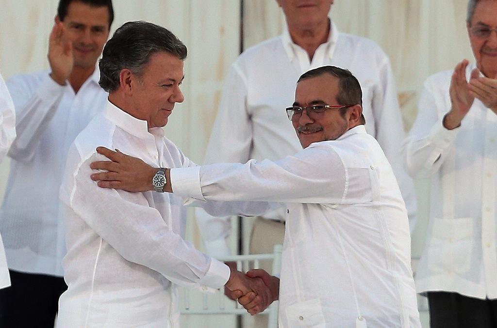 Colombias Juan Manuel Santos (till vänster i förgrunden) skakar hand med Farcledaren Rodrigo Londoño i samband med undertecknandet av fredsavtalet den 26 september. Uppgörelsen förkastades i en folkomröstning, och i dag ska en omarbetad version av fredsavtalet undertecknas vid en ceremoni. (Foto: Fernando Vergara/AP/TT-arkivbild)