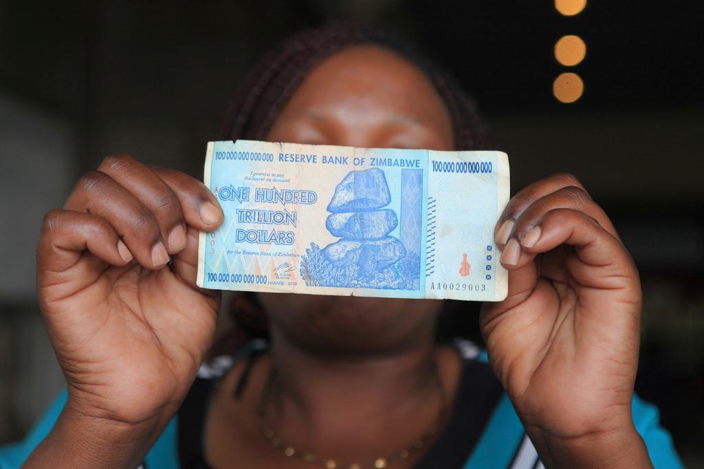 
För sju år sedan övergav Zimbabwe sin egen valuta till följd av hyperinflation. På bilden håller en kvinna upp en numera ogiltig sedel med valören "one hundred trillion dollars". (Foto: Tsvangirayi Mukwazhi/AP/TT-arkivbild)