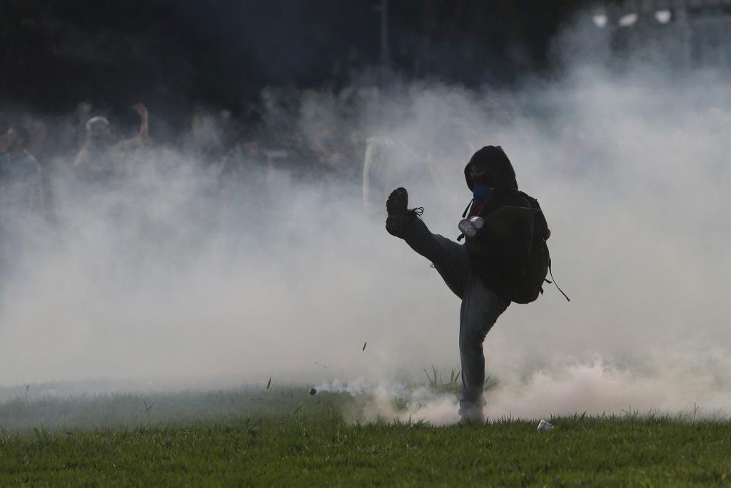 
En demonstrant sparkar tillbaka en tårgasgranat under protesterna i Brasilia. (Foto: Eraldo Peres/AP/TT)