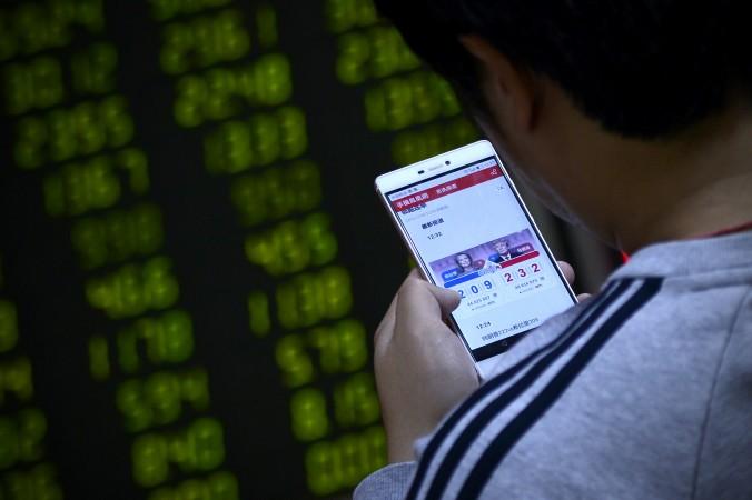 En kinesisk investerare i Peking följer det amerikanska presidentvalet på sin smartphone. (Foto: Wang Zhao/AFP/Getty Images)