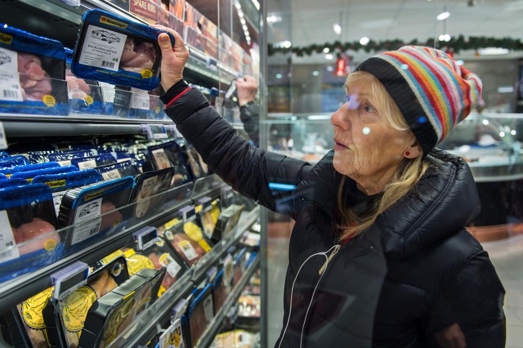 Carita Högmark, 67, letar bland kycklingförpackningarna i en livsmedelsbutik i Stockholm. Hon är beredd att betala lite mer för svensk kyckling med ursprungsmärkning. "Jag vill absolut veta vad jag stoppar i mig. Helst ska det vara kyckling från svenska gårdar. Den smakar bättre, och då behöver man inte vara så orolig för smitta." (Foto: Stina Stjernkvist/TT)