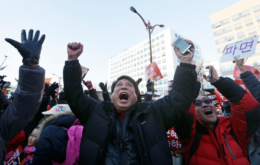 Demonstranter firar utanför parlamentet i Seoul den 9 december sedan församlingen därinne beslutat ställa president Park Gyun-Hye inför riksrätt. (Foto: Ahn Young-joon/AP/TT)