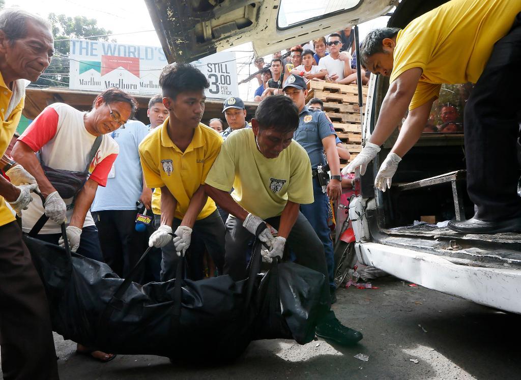 Några Manilabor tittar på medan liket efter en av de fem personer som dödats i ett påstått knarktillslag i november transporteras bort. Över 5 000 människor har dödats i president Rodrigo Dutertes antidrogkrig sedan han tillträdde den sista juni förra året. (Foto: Bullit Marquez/AP)