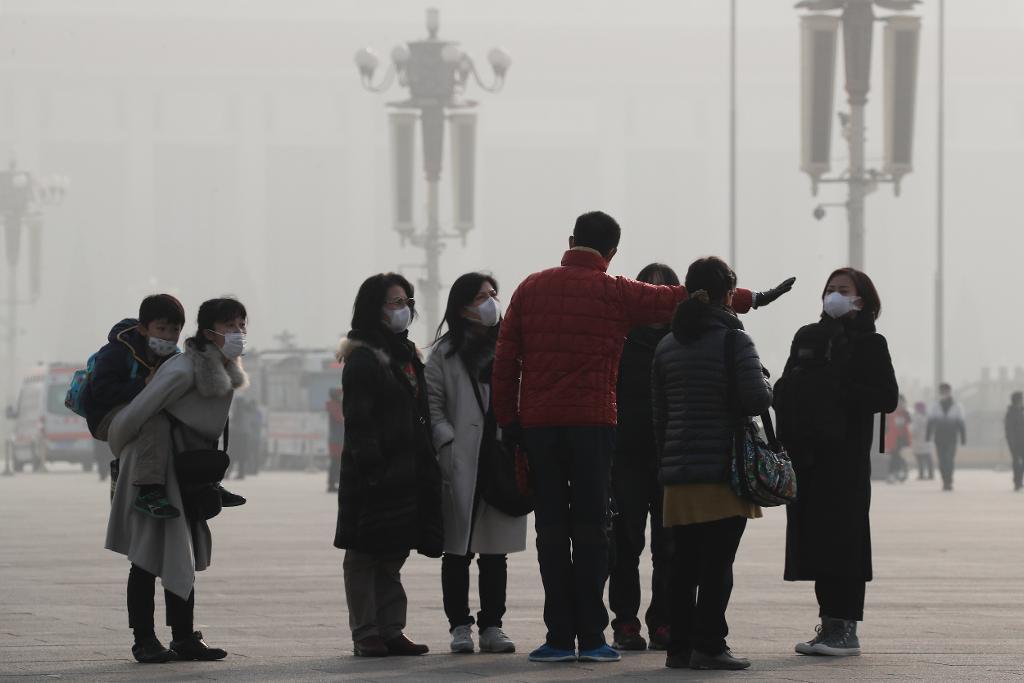 Peking och andra kinesiska städer har de senaste veckorna varit insvepta i tjock smog. Här turister med andningsmasker vid Himmelska fridens torg. (Foto: Andy Wong/AP/TT-arkivbild)