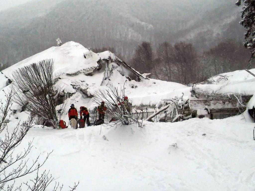 Räddningsarbetare framför det italienska hotell som begravts av en lavin. (Foto: CNSAS-AP-TT)