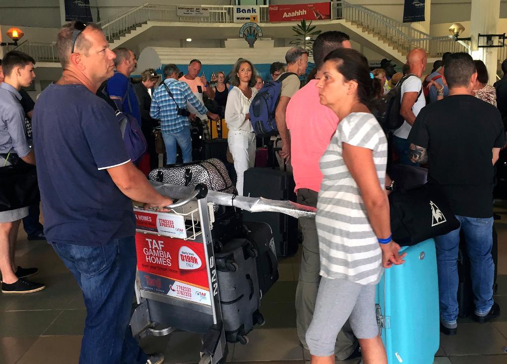 Utländska turister trängs på flygplatsen i Banjul i Gambia där specialchartrade plan börjat flyga hem bland annat brittiska turister. (Foto: AP/TT)