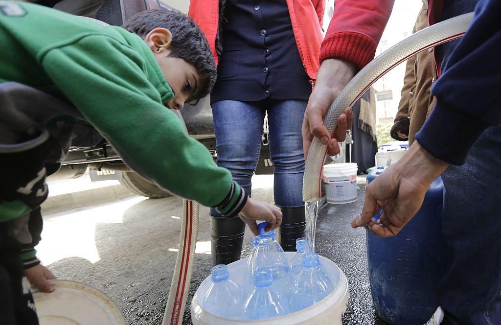 Syrier fyller vattenflaskorna med vatten. Miljoner människor har varit utan vatten i veckor efter att försörjningen skadades i Wadi Barada, där Damaskus huvudkälla ligger.  
(Foto: Louai Beshara /AFP/Getty Images)
