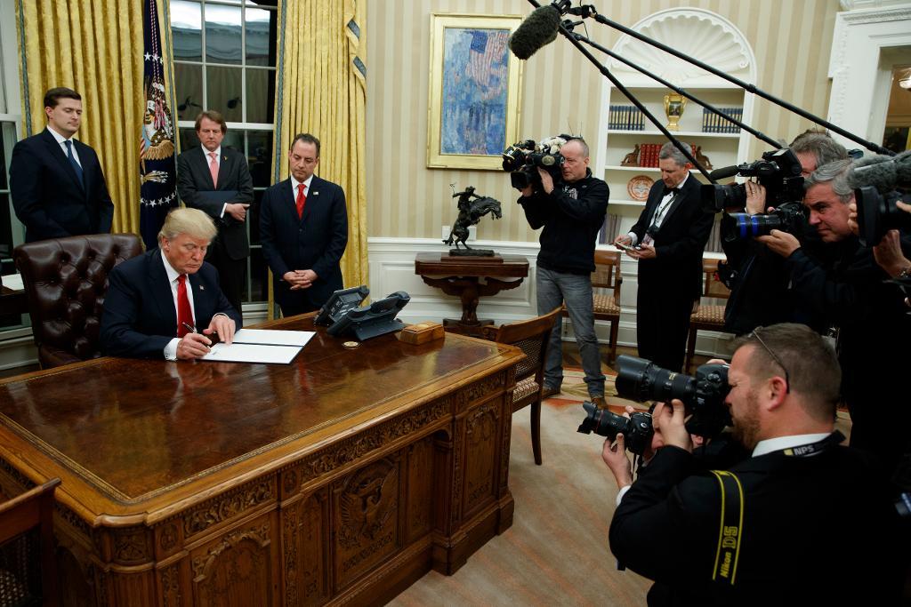 Donald Trump skriver på sitt första beslut som president. (Foto: Evan Vucci/AP/TT)