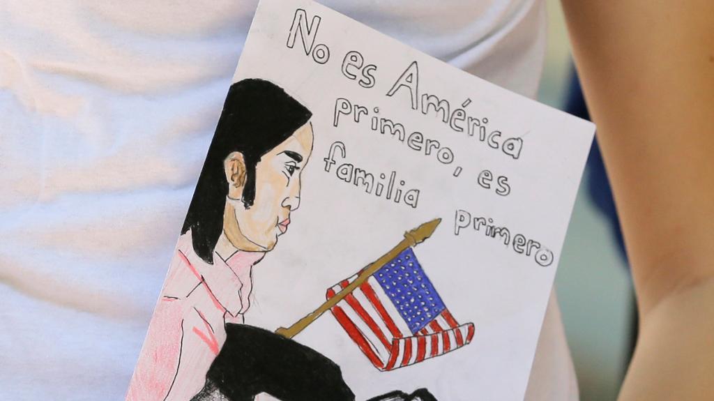 Ett barn till en invandrare i USA håller i en skylt med texten: Det är inte USA först, utan familjen först. Foto: Alan Diaz/AP/TT-arkivbild