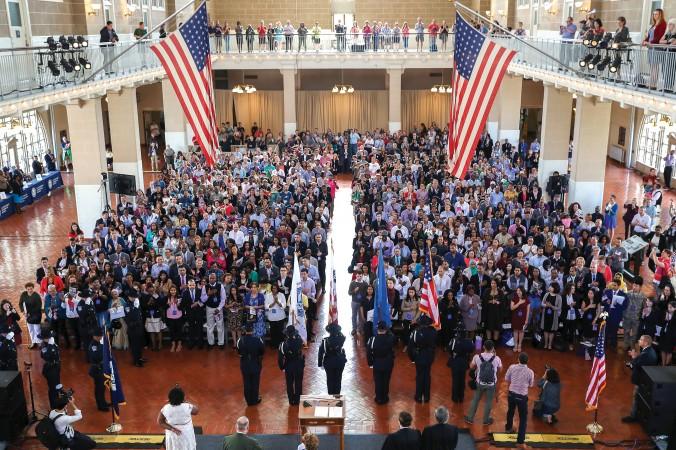 Amerikanska invandrare står upp under nationalsången vid en medborgarskapsceremoni på Ellis Island i New York,16 september 2016. (Foto: John Moore/Getty Images)