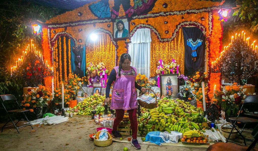 En kvinna placerar ut offergåvor inför De dödas dag (Alla helgons dag) i byn Santa Fe de la Laguna, Mexico. Den dagen ska inte förväxlas med Halloween, med sina fester och maskerader, men båda dagarna anknyter till döden och de döda. Foto: Enrique Castro/AFP via Getty Images